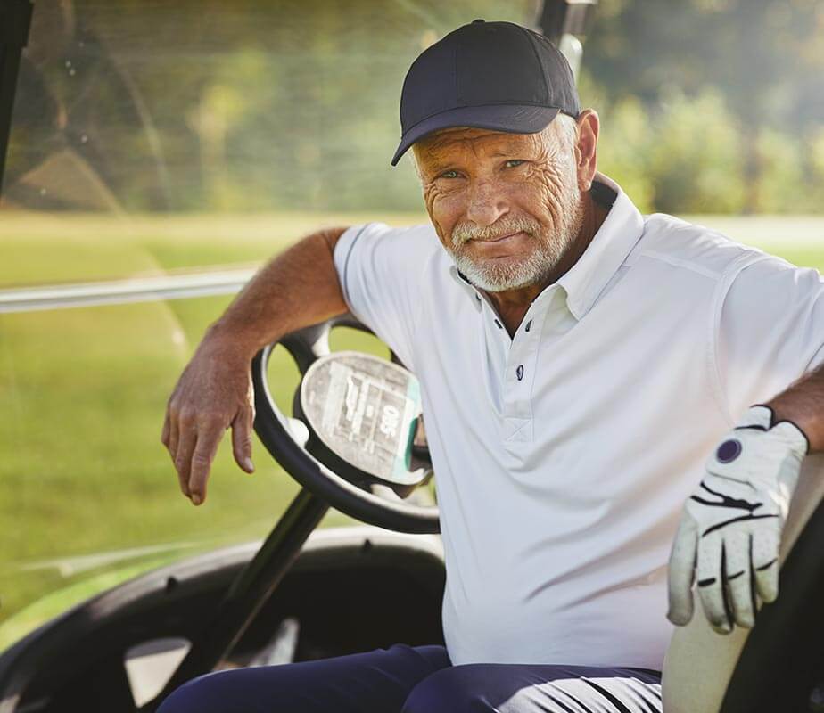 Older man sitting in a golf cart on a golf course
