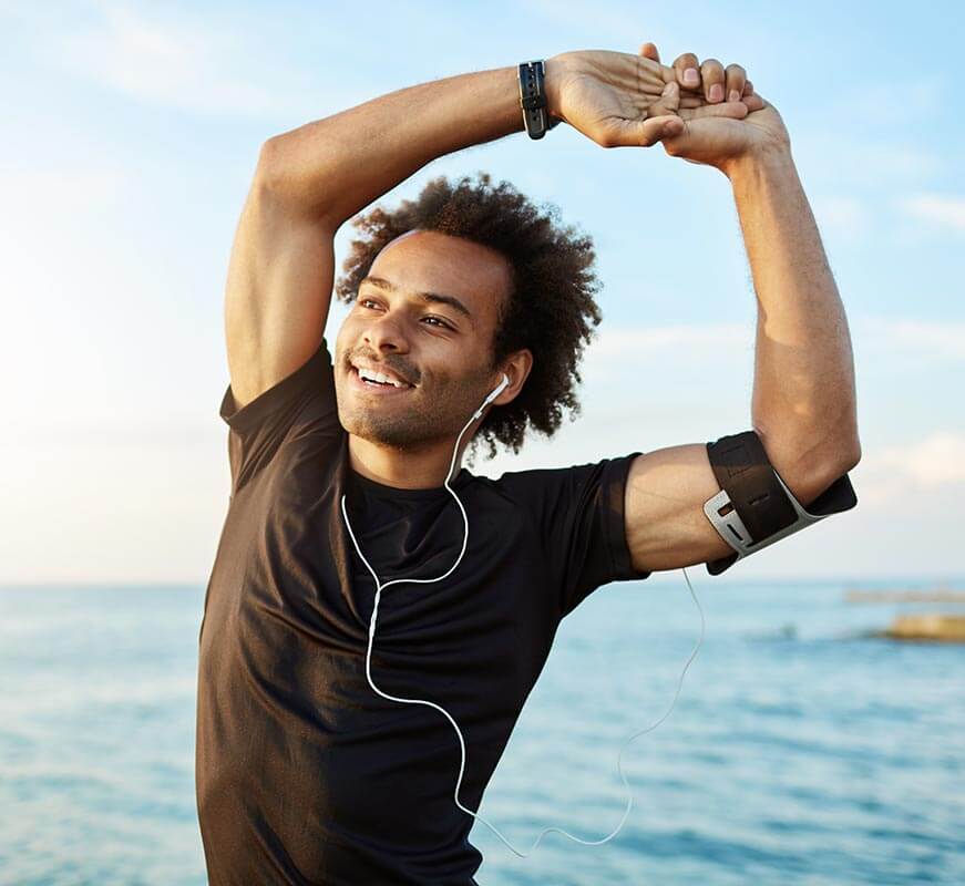 Smiling young man stretching in workout clothes