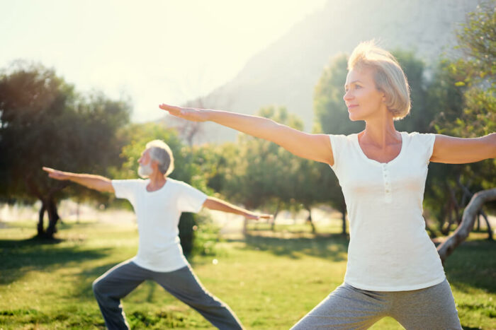 Older man and woman doing yoga ouside